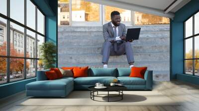 Happy African American on the street with laptop, freelancing Wall mural