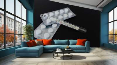 Tablets and a thermometer on a black background Wall mural