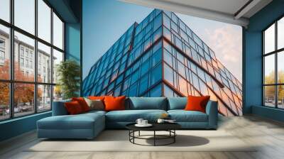 Low angle view of a modern glass office building against a blue sky. Wall mural