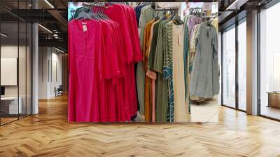 Female casual clothes in boutique, clothes with a selection of ladies fashion, Colorful women's dresses on hangers in a retail shop in India. Wall mural