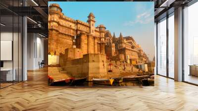 India, Varanasi Ganges river ghat with ancient city architecture as viewed from a boat on the river at sunset. Wall mural