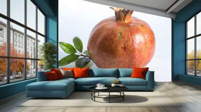 A ripe pomegranate with green leaves on a white background. Wall mural