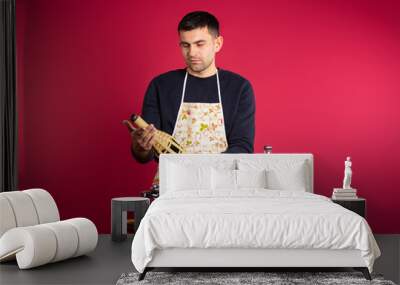 Gender stereotype. The man in the kitchen, preparing dinner and choosing his favorite drink. Wall mural