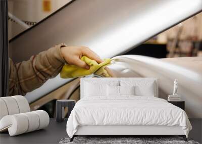 Person cleaning car with yellow cloth on hood and rims Wall mural