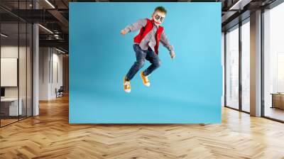 Scary funny boy in Joker costume and face art jumping on sky blue colored background with free down and side space. Cute kid wearing halloween costume, copy space available. Wall mural