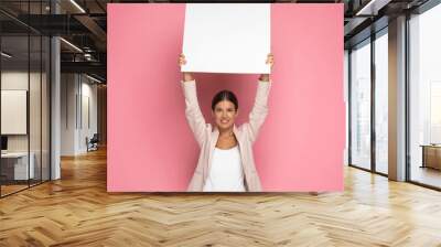 businesswoman holding a blank billboard overhead and smiling Wall mural