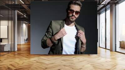 Close up of determined man adjusting his green jacket's collar Wall mural