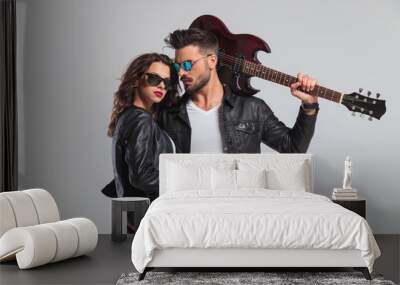 cool punk man holding guitar on shoulder and embracing woman Wall mural