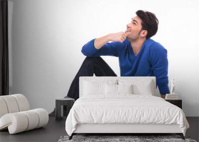 seated young man in blue jeans and shirt looking up Wall mural