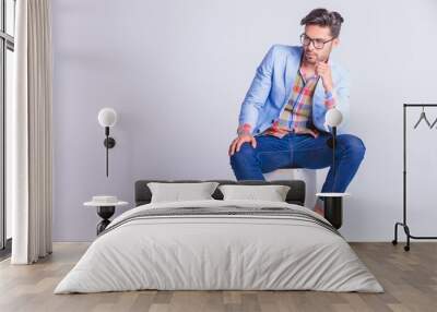 smart casual man seated on box, wearing glasses Wall mural