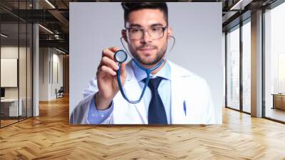 young doctor holding up stethoscope Wall mural