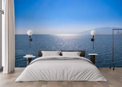 Seascape with blue sky and waters, with distant land hidden in the mist. Wall mural