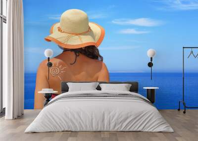 Sun made of sunblock on woman back with seascape background Wall mural