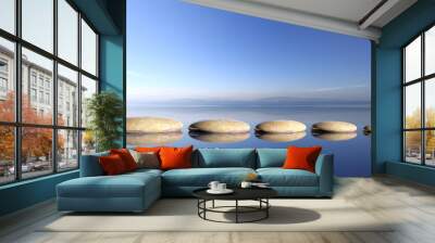 zen stones row from large to small in water with blue sky and peaceful landscape background Wall mural