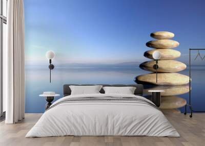 Zen stones stack from large to small  in water with blue sky and peaceful landscape background. Wall mural