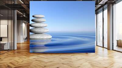 Zen stones stack from large to small  in water with circular waves and blue sky. Wall mural