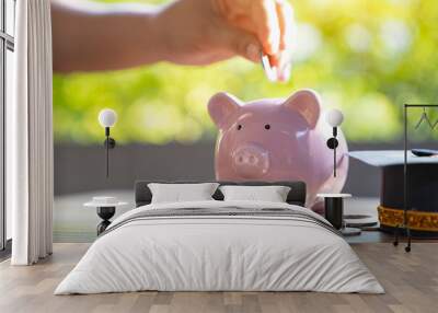 Hand putting money coin into piggy bank, saving money education Wall mural