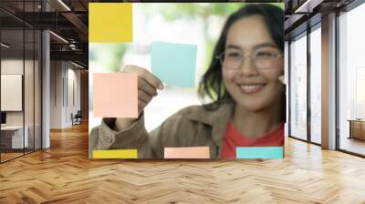 The young woman is jotting down business ideas on a sticky note Wall mural