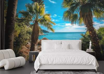 Palm trees by the sea on a summer day at a secluded beach with rocky shoreline Wall mural