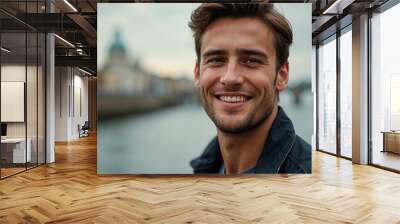 young smiling handsome man smiling portait photo river bridge cityscape blurred background Wall mural