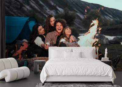 Beautiful teens with large white smile have a good time together at camping , playing with some lightning sparklers Wall mural