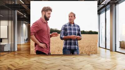 Two farmers stand in a wheat field .Agronomists discuss harvest and crops among ears of wheat Wall mural