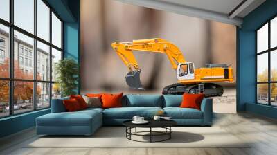 Yellow excavator model toy performs excavation work on a construction site. (Image stacking technique) Wall mural