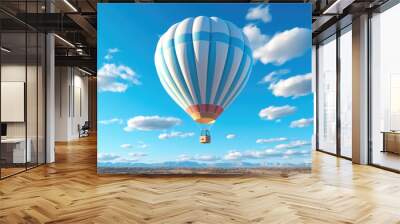 A white hot air balloon floats weightlessly across a bright blue sky. Wall mural