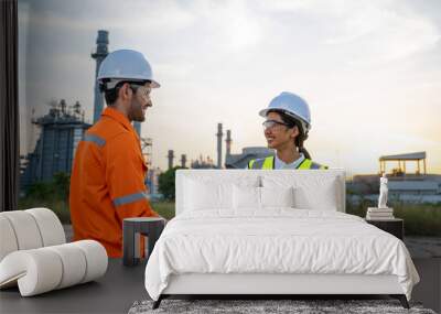 Engineers shaking hands at front refinery construction site. Wall mural