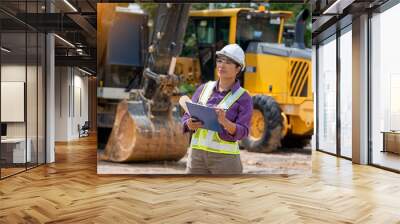 Female engineer worker on construction site outdoors with excavator in background,construction Site,construction machinery, bulldozer, excavation. Wall mural