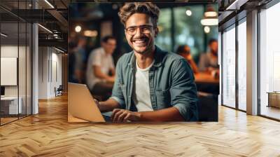 Smiling web designer using laptop at vibrant co-working space. Wall mural