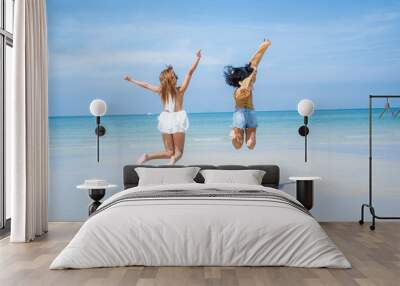 Two attractive girls jumping on the beach,Having Fun,Summer Lifestyle. Wall mural