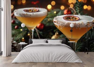 Two glasses of martinis with white foam and passion fruit on the rim, sitting next to each other. placed in front of an oak table with greenery and decorations. Christmas lights are in the background. Wall mural