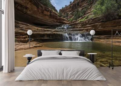 A cascading waterfall flows down a series of sandstone cliffs into a crystal-clear pool. Wall mural