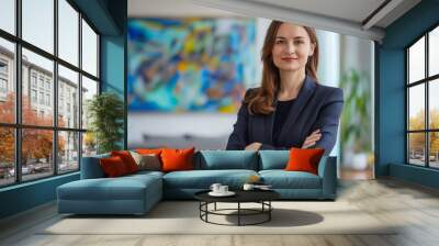 A business woman standing in an office with her arms crossed. Wall mural