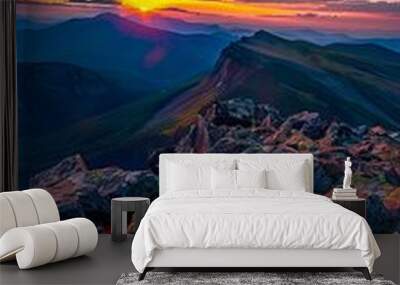 A colorful sunset over a mountain range with rocks in the foreground Wall mural