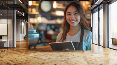 A smiling woman holding a tablet in a coffee shop. Wall mural