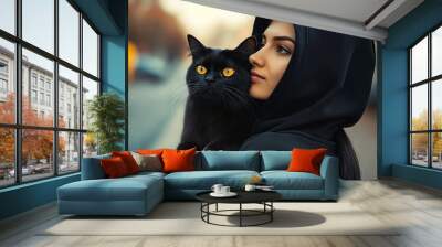 A woman in a black hoodie holding a black cat Wall mural