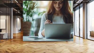 Business woman sitting at office table using mobile phone while online working on laptop computer at home office, business casual, telecommuting, working from home, close, Generative AI Wall mural