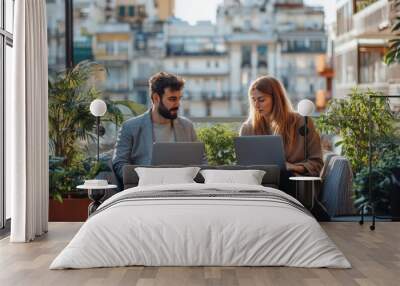 Two young business people with laptop sitting on a terrace outside office, working, Generative AI Wall mural