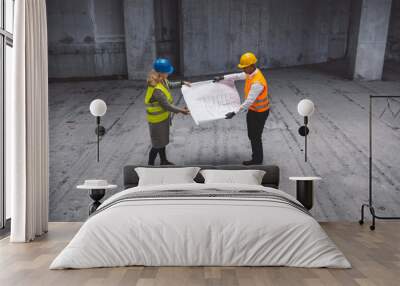 Construction industry and engineering - engineers, architects and contractors on the construction site analyzing the development of the building Wall mural