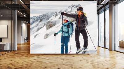 Couple of ski tourers looking at the views of the snowy Alps from high up  Wall mural