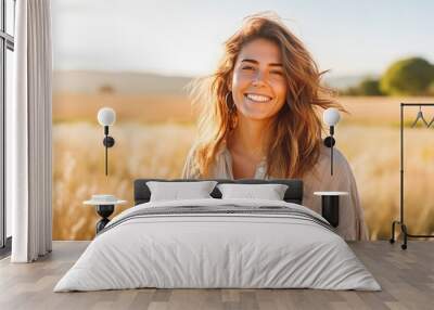 Portrait of beautiful young caucasian woman smiling while standing in field of wheat, natural light Wall mural