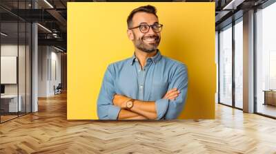 Portrait of handsome cheerful young businessman pointing at something. Professional young man in a suit on yellow background making hand gesture. Wall mural