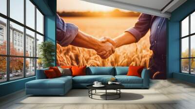 Two farmers shake hands in front of wheat field. Male farmer shaking hands while standing in cultivated green corn field during sunset against sky Wall mural