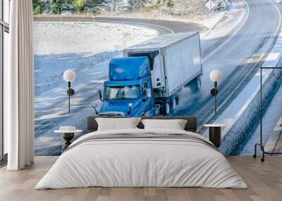 Big rig blue day cab semi truck transporting cargo in reefer semi trailer driving on winter wet road with snow Wall mural