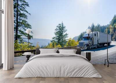 Big rig white classic semi truck transporting cargo in refrigerated semi trailer on winding autumn road Wall mural