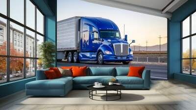 Bright blue powerful big rig semi truck transporting cargo in reefer semi trailer driving on the road with sunset Wall mural