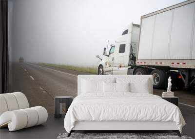 Broken white big rig semi truck with dry van semi trailer stands on the side of a foggy road waiting for mobile roadside assistance Wall mural