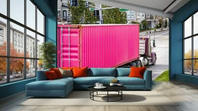 Classic big rig day cab semi truck tractor transporting bright pink container on semi trailer driving on the urban city street Wall mural